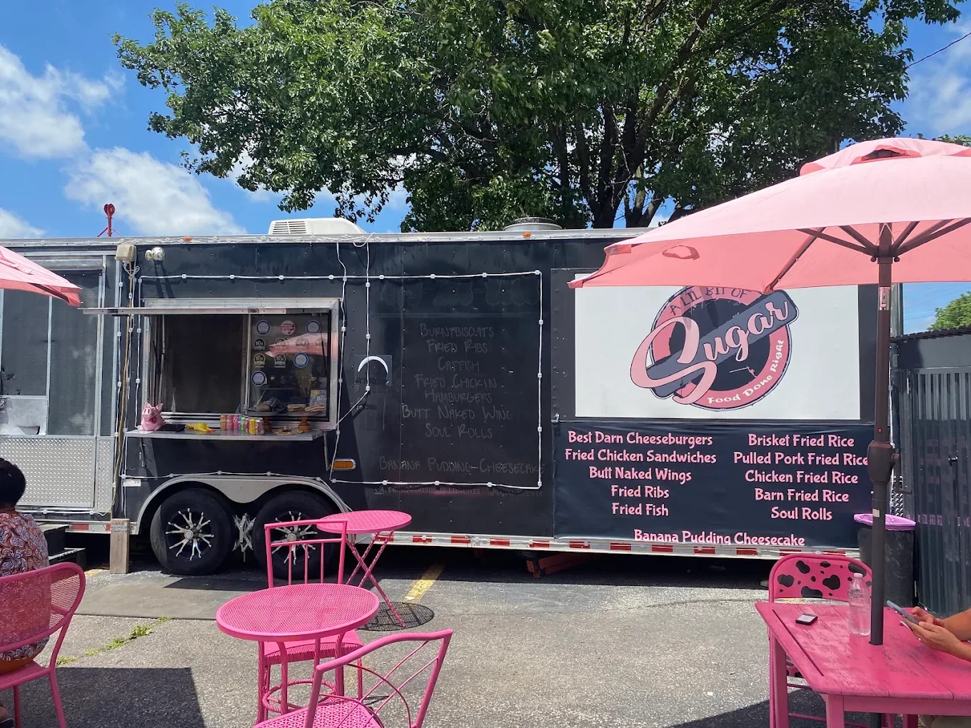 A Lil Bit Of Sugar black food truck with signature pink umbrellas and outdoor café tables in Gravette